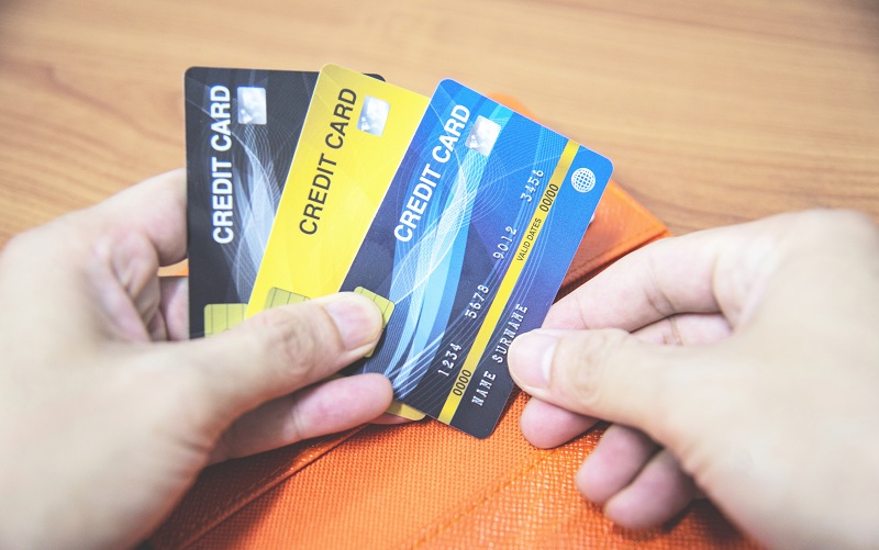 mão masculina segurando três cartões de crédito aleatórios, para escolher o melhor tipo de cartão de crédito