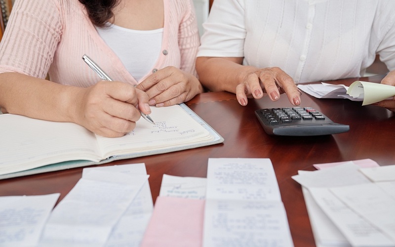 casal com calculadora e anotações vendo como calcular os juros do cheque especial